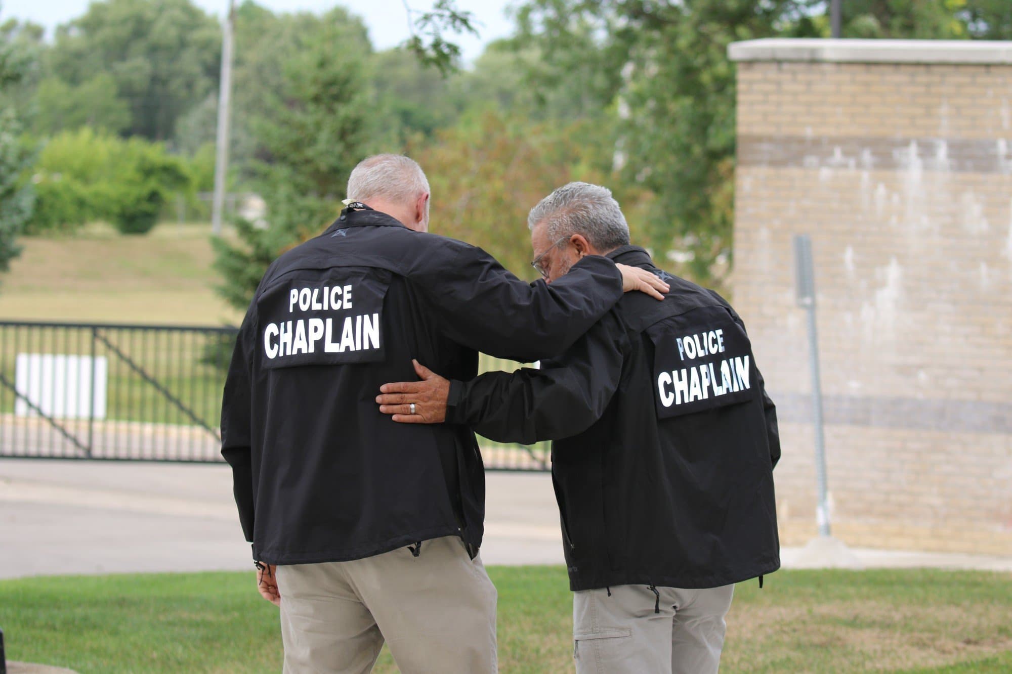 Two police chaplains standing together, one with an arm around the other's shoulder